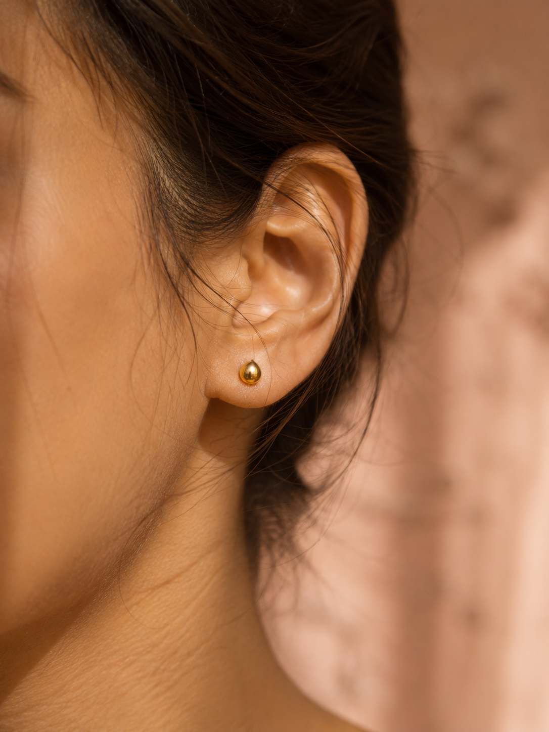 A gold hoop earring close-up on a soft surface